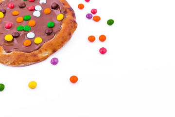 Chocolate pizza with colored sweets on a white background