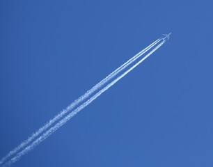 Passenger plane in blue sky with white reversible track