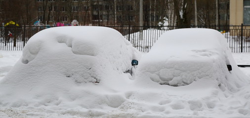 Snow-covered cars parked in the yard of a house