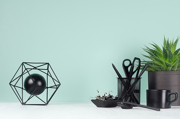 Home interior - workplace with black stationery, green house plant, coffee cup, aloe plant, abstract atom model in green mint menthe color on white wood desk, copy space.