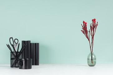 Fresh spring office workplace for business - black stationery, books, elegant decorative red branch, coffee cup on green mint menthe wall and white wood table.