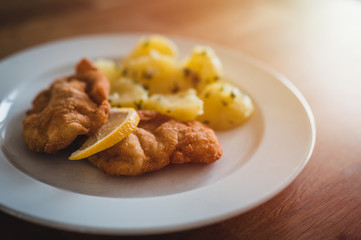 Steak with boiled potatoes on a white plate.