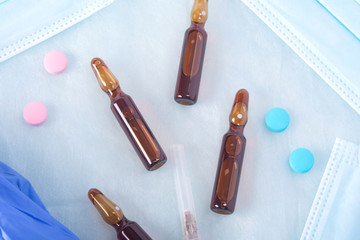 background, from a set of medical tissue, dark ampoules with drugs, multi-colored tablets and a syringe needle