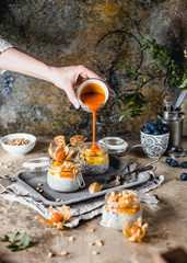  pudding with chia seeds in jars with mango slices and pine nuts on shabby beige background, healthy breakfast concept