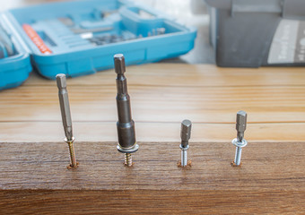 Wood drill screw with drill bit of each type and size on the table, wood background, screws made od steel.