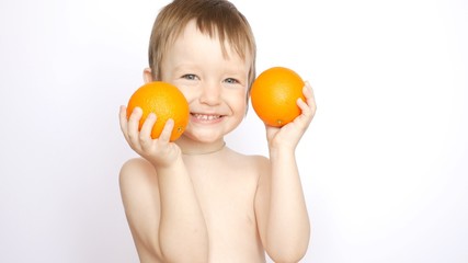 A very beautiful boy poses with two fresh oranges in hands