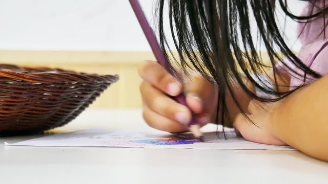 Kindergarten children use colored pencils to paint the pictures on paper.