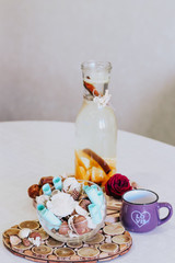Fototapeta na wymiar Decanter with water oranges and cinnamon. Dates. Rose flower. A vase with dried flowers with leaves with wishes. And a purple cup. Iftar pop sunnae, dates and water. Ramadan.