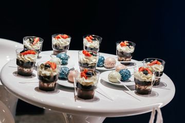 Desserts with whipped cream and strawberries on a white table. Glamorous style