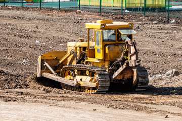 Yellow bulldozer leveling the ground at a construction site
