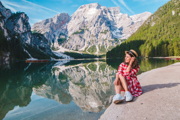 woman in red checkered dress with straw hat looking at mountain lake