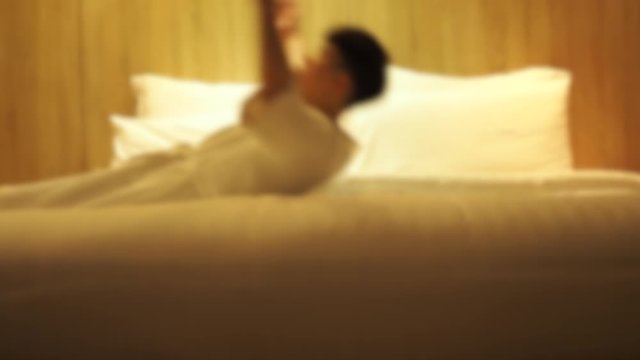 Blurred effect on man falling asleep on bed, looking tired