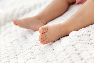 Obraz na płótnie Canvas Closeup of baby legs on knitted white blanket as a background at natural light