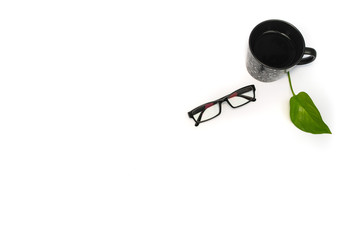 Eyeglasses and cup with green leaf on white background