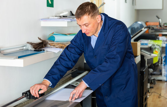 Printing Worker Cuts Paper On A Cutter Machine