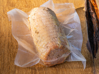 Pork ham in vacuum packaging on a wooden table