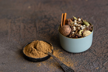 Different spices black and white peppercorns, cloves, cinnamon, mace, cardamom, cumin. Spice blend of ground spices in metal bowl  and spice blend for cooking.