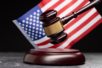 Close up of symbol of law and court. Wooden gavel on background of American flag on black background