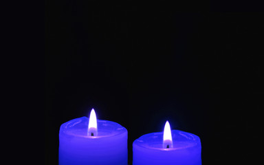 Obraz na płótnie Canvas Shining Two Royal Blue Candles on Black Background with Copy Space 