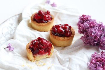 Tarts with fresh cherry and custard, delicious dessert on a white background, close-up.