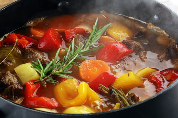Meat stew with vegetables. Beef stew with potatoes, carrots and fresh herbs on table.