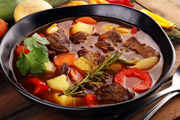 Meat stew with vegetables. Beef stew with potatoes, carrots and fresh herbs on table.