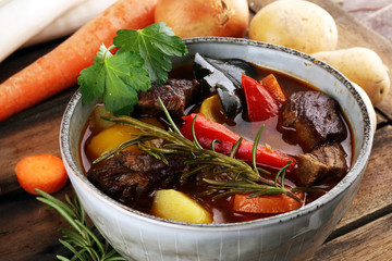 Meat stew with vegetables. Beef stew with potatoes, carrots and fresh herbs on table.