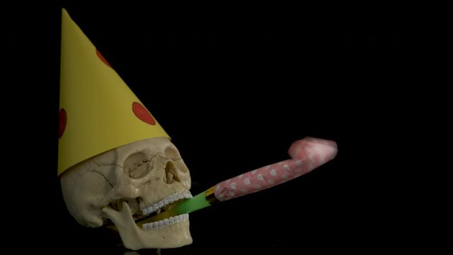 Horror birthday. Sad birthday. Skull with party horn and cap.