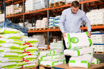Man choosing compost soil in plastic bags in hypermarket