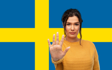people, prohibition and rejection concept - serious young woman showing stop gesture over flag of...