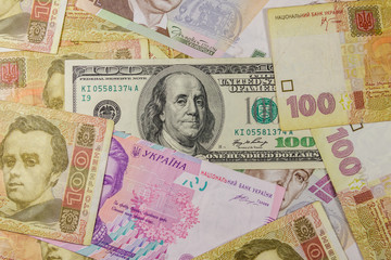 One hundred dollar bill on a background of different ukrainian hryvnia banknotes