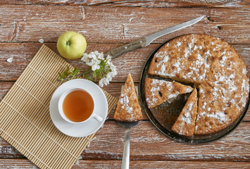 Homemade pie with cherries and apples white cup of tea on a dark rustic wooden board background. Rustic style food