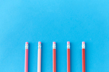 drawing, education and object concept - five lead pencils with eraser on tip on blue background