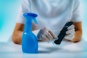 Disinfecting Remote Controller. Woman Disinfecting Remote Controller with Alcohol-based disinfectant