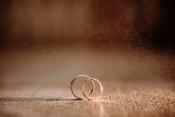 two gold rings on a flat surface with drops of water falling on them