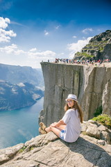 Hiker girl on Prekestulen Mountain, Norway. Girl tourist in the mountains of Norway. Pulpit Rock. Preikestolen, Norge.