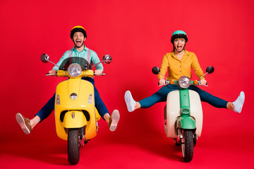 Portrait of nice attractive funky foolish careless cheerful cheery glad couple driving moped having fun spending time isolated over bright vivid shine vibrant red color background