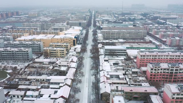 Linear shot of the central road and panorama of a city in China on a snowy day.