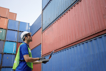Foreman uniform using laptop check orders and control container transportation and export with commercial docks with shipping yard logistics.