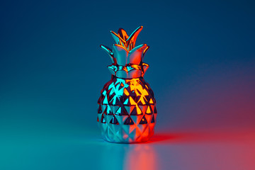 Decorative pineapple in neon light, tropical fruit in disco style