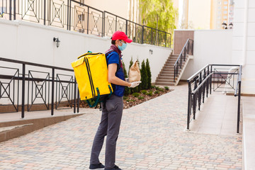 Portrait of a cheerful delivery man standing with yellow thermo backpack for food delivery on the street outdoors