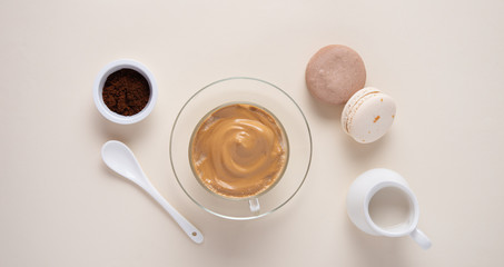 dalgona coffee in a glass Cup with macaroon, instant coffee  and  milk jug on light yellow...