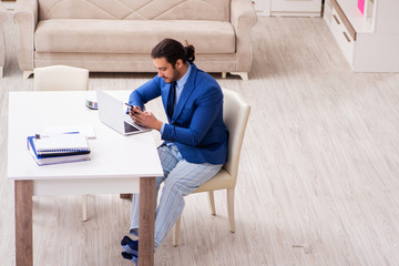 Young male employee working from house in self-isolation concept