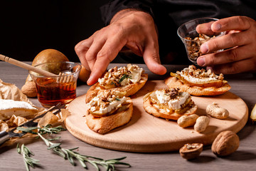 Food recipe background. chef preparing delicious bruschettas with brie camembert cheese, pear nuts...