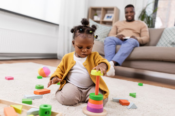Obraz premium childhood and people concept - little african american baby girl playing with toy blocks at home