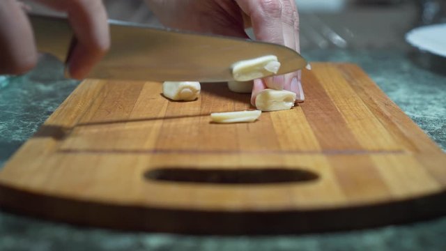 Cutting garlic with a sharp knife. The hands of the chef with a knife. Restaurant kitchen. Mexico, healthy.