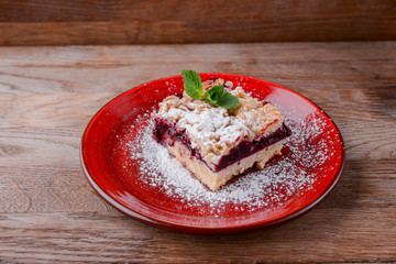 A piece of cherry pie closeup. Served on a red plate over dark rustic wooden background. Copy space banner.