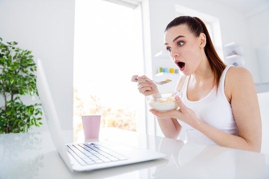 Photo of shocked housewife lady sit morning kitchen browsing notebook watch thriller movie freelancer have breakfast eat cereal corn flakes stay home distance remote work quarantine indoors - Powered by Adobe