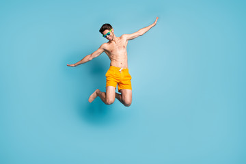 Fototapeta na wymiar Full length body size view of his he nice attractive cheerful careless guy in swimming shorts jumping having fun time isolated on bright vivid shine vibrant green blue turquoise color background