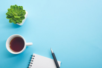 Blue desk office with laptop, smartphone and other work supplies with cup of coffee. Top view with...